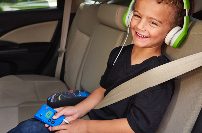young child sitting in a car using a Playaway device